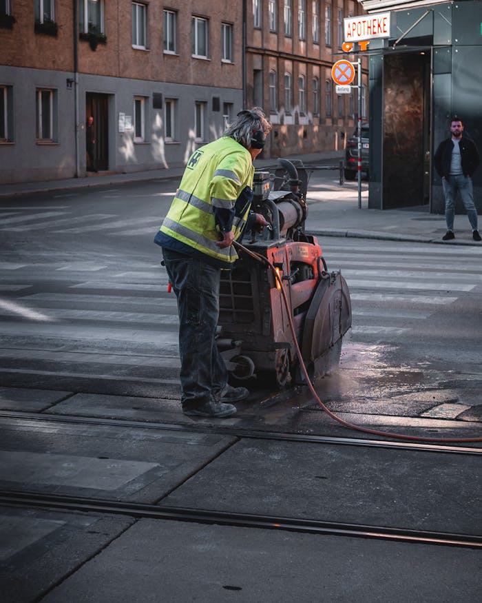 Construction worker using machinery on a street in Vienna, Austria during the day.